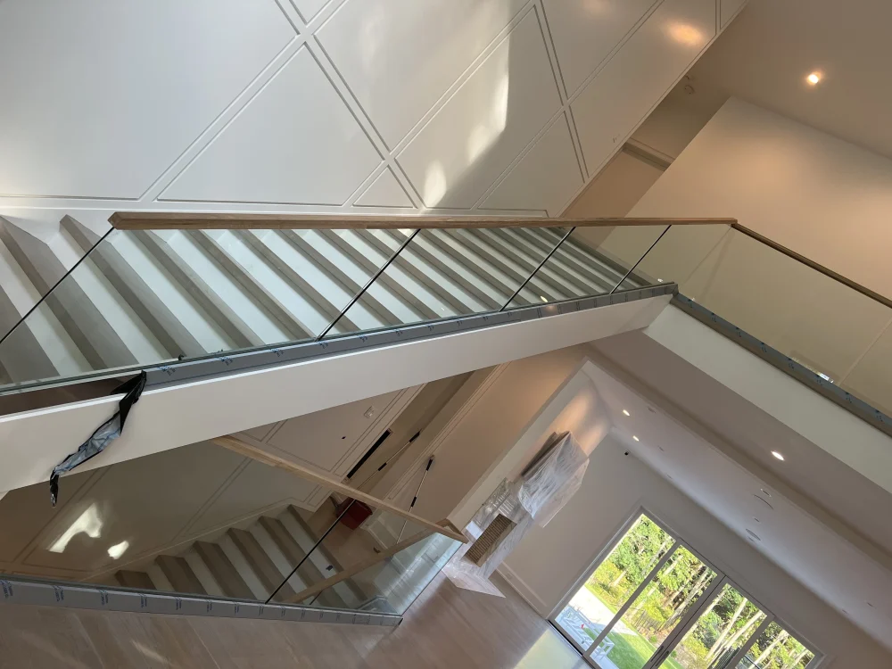 Elegant glass railing with wood handrail for modern staircase.