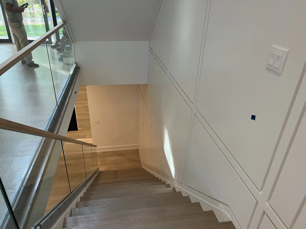 Elegant glass railing with wood handrail for modern staircase.