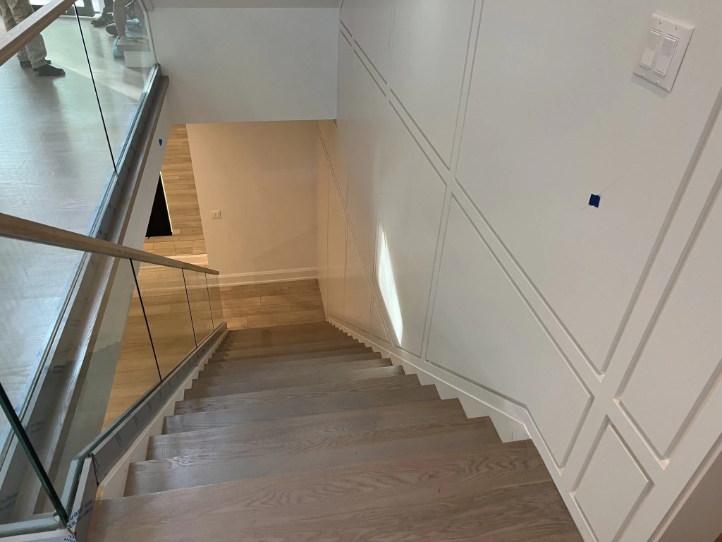 Modern staircase with wood finish and glass railing in a contemporary home.