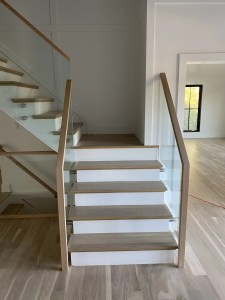 Modern staircase with wood handrails and glass balustrades.